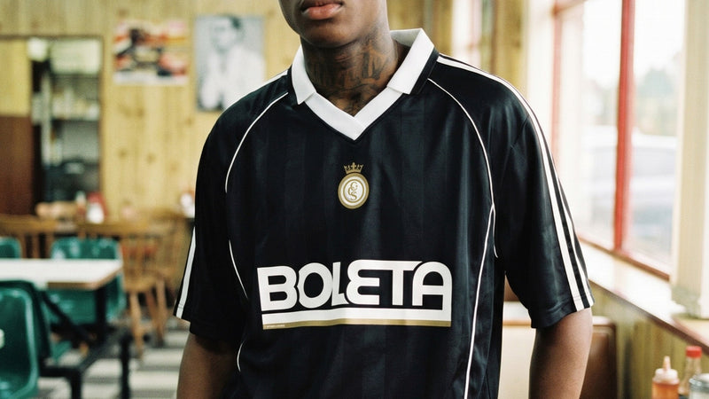 Un modelo llevando la camiseta de fútbol negra «Boleta» de Caracas Merch en la calle