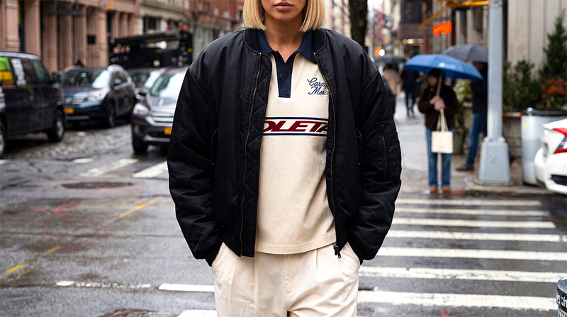 Hombre con una chaqueta negra y una camiseta de Caracas Merch cruzando la calle