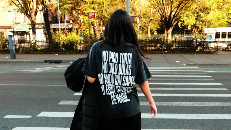 Mujer de espaldas cruzando la calle con una camiseta de Caracas Merch con texto estampado