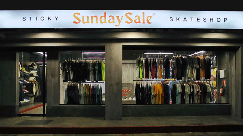 Fachada nocturna de la tienda Sticky Sunday Sale Skateshop