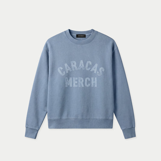 Blue oversized vintage wash crewneck by Caracas Merch with arched “Caracas Merch” logo at chest, front view