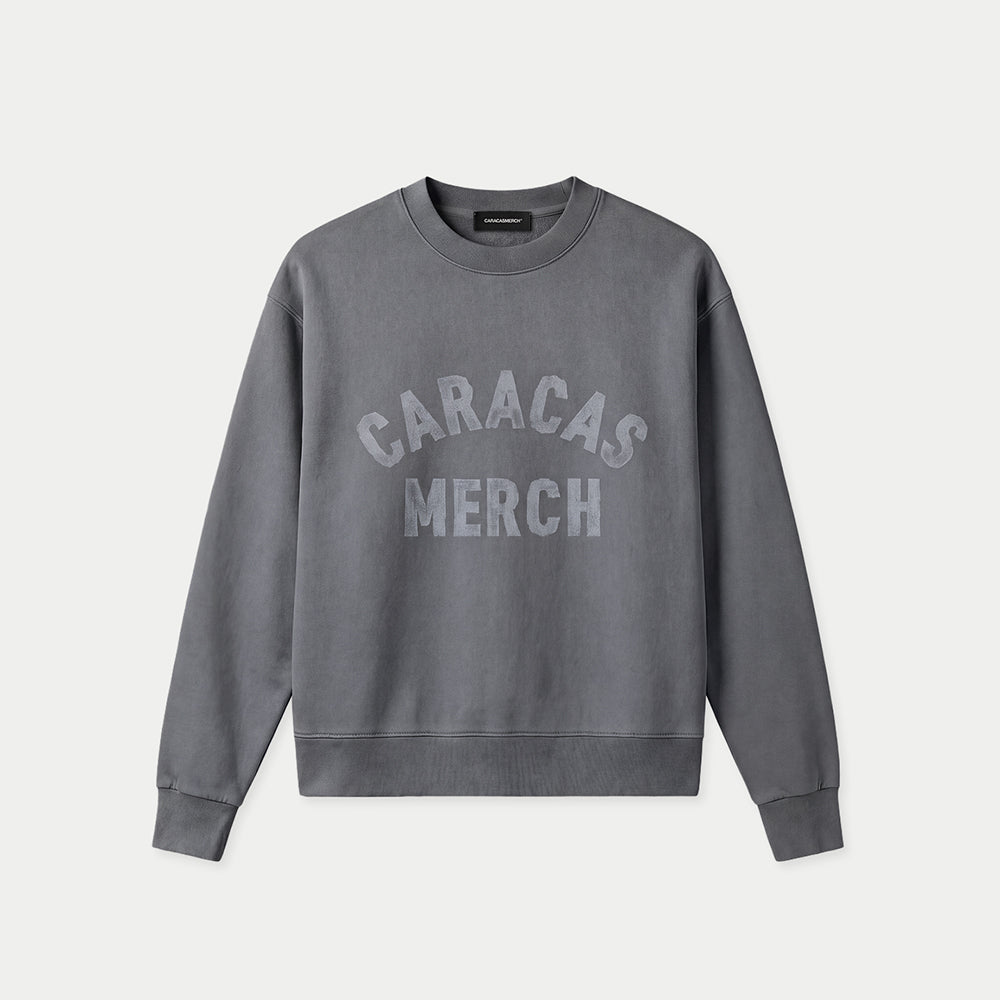 Grauer Oversized Vintage-Wash-Crewneck von Caracas Merch mit gebogenem „Caracas Merch“-Logo auf der Brust, Vorderansicht