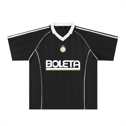 Black soccer-style jersey front view with striped texture, V-neck collar, and bold “BOLETA” graphic across the chest – Caracas Merch