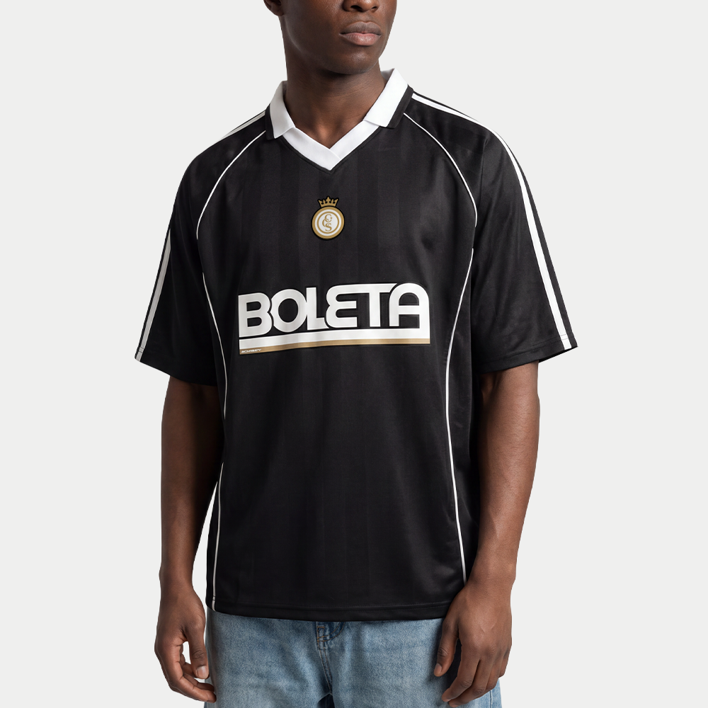 Male model wearing black soccer-style jersey front view with striped texture, V-neck collar, and bold “BOLETA” graphic across the chest – Caracas Merch