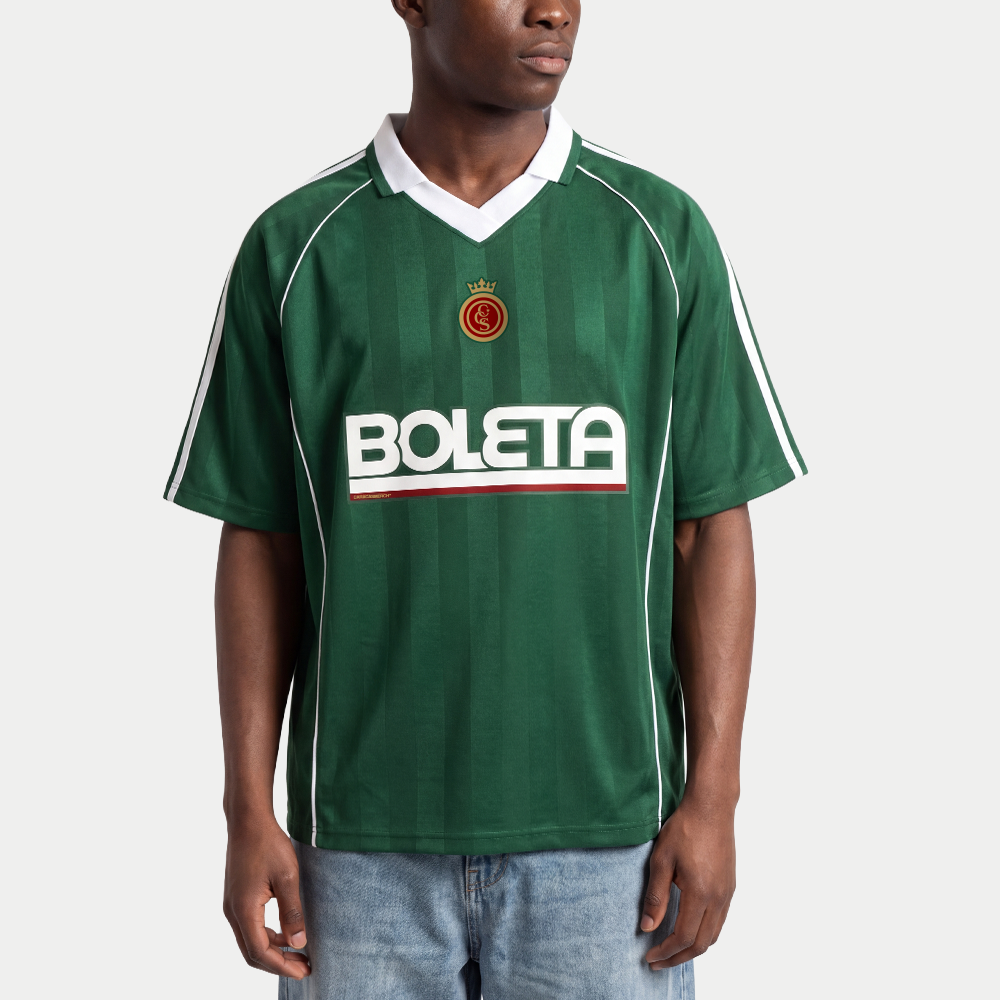 Male model wearing green soccer-style jersey front view with striped texture, V-neck collar, and bold “BOLETA” graphic across the chest – Caracas Merch