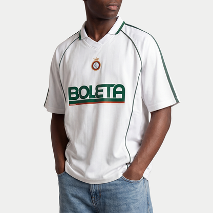 Male model wearing white soccer-style jersey front view with striped texture, V-neck collar, and bold “BOLETA” graphic across the chest – Caracas Merch