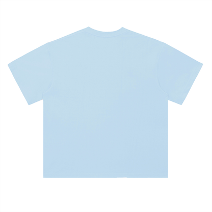 Light blue oversized t-shirt back view with collage-style graphic featuring paint palette, brushes, and vintage classroom images with “Caracas” text – Caracas Merch