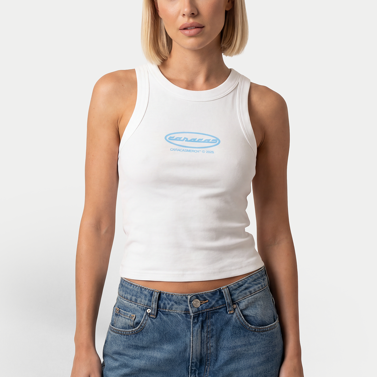 Female model wearing white tank top with blue Caracas logo by Caracas Merch