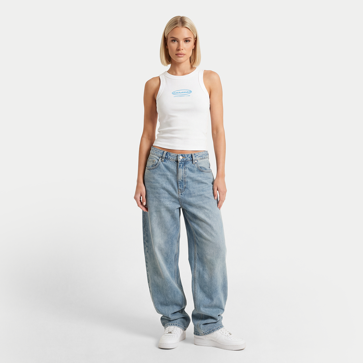 Female model wearing white tank top with blue Caracas logo full body view