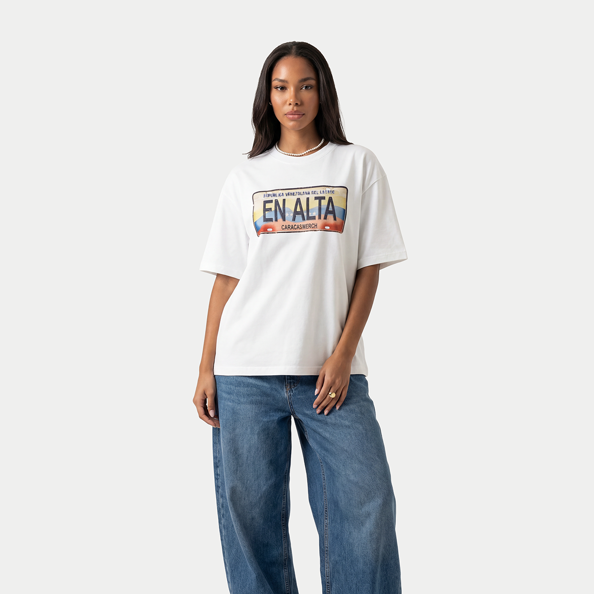 Female model wearing white En Alta license plate graphic t-shirt by Caracas Merch