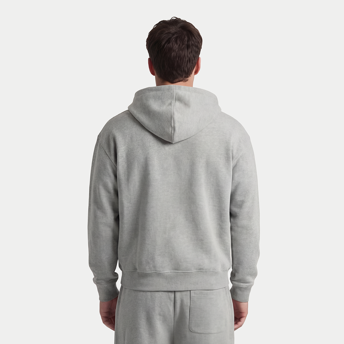 Back view of male model wearing gray zip-up hoodie and sweatpants by Caracas Merch