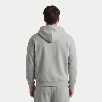 Back view of male model wearing gray zip-up hoodie and sweatpants by Caracas Merch