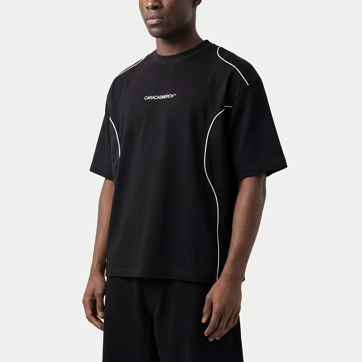 Black performance streetwear t-shirt worn by model with contrast white piping