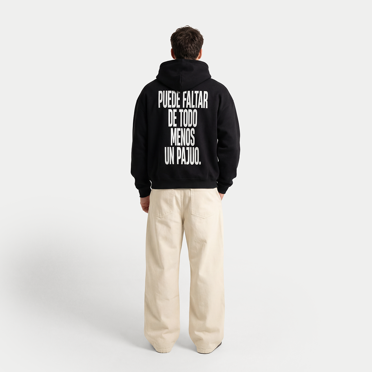 Full body back view of model wearing black “Puede faltar de todo menos un pajuo” hoodie