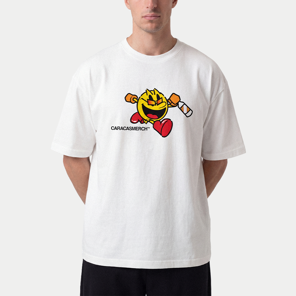 Male model wearing white oversized t-shirt front view with cartoon running character graphic holding a bottle and Caracas Merch logo underneath