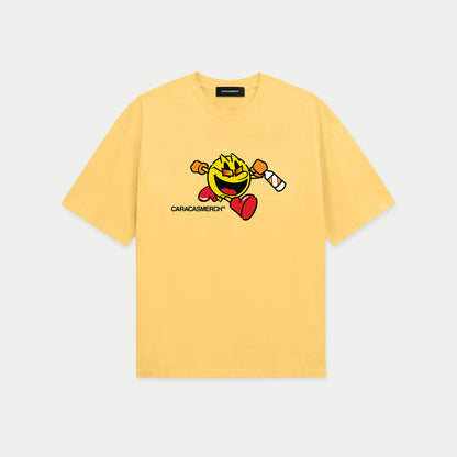 Yellow oversized t-shirt front view with cartoon running character graphic holding a bottle and Caracas Merch logo underneath