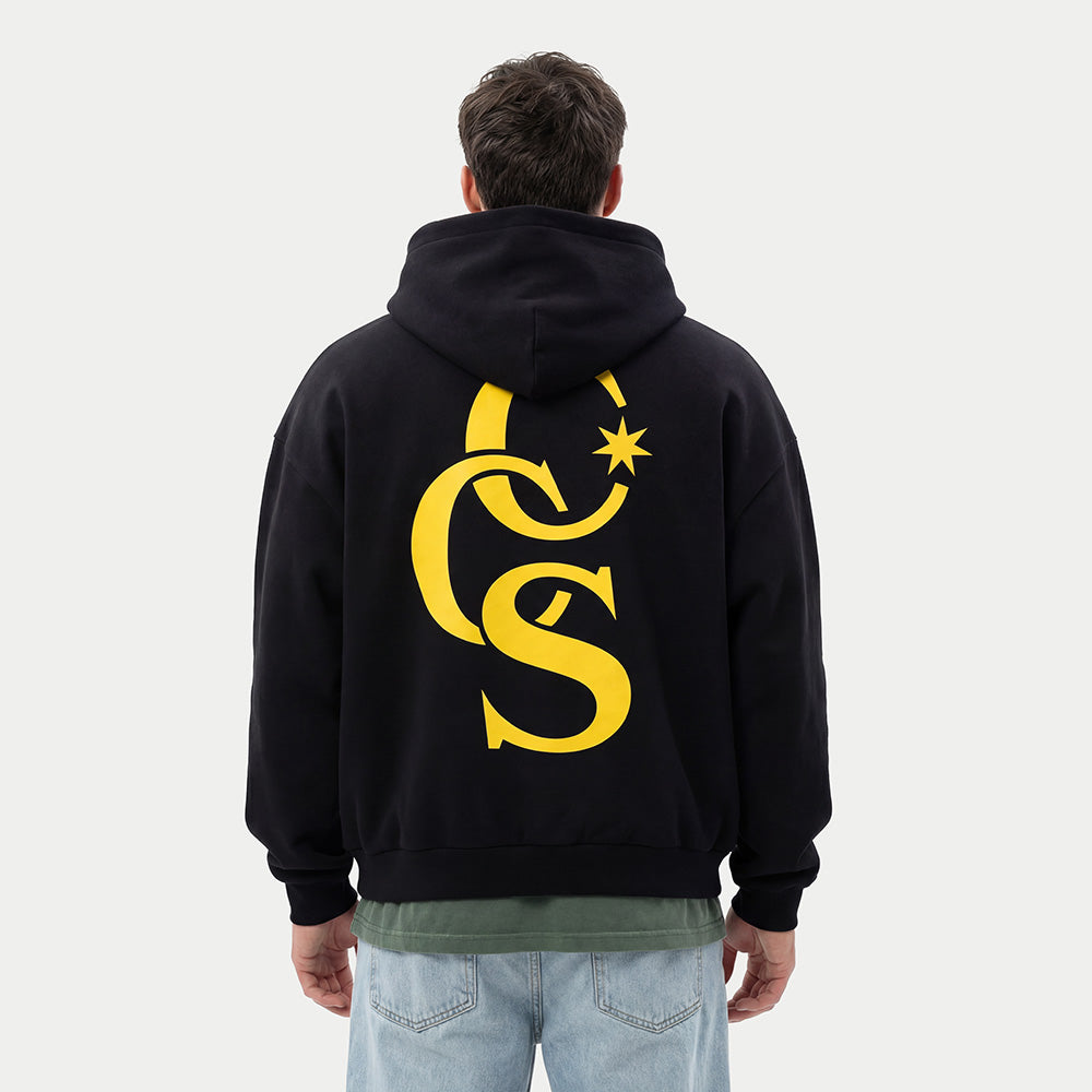 model wearing CCS Monogram Hoodie black with yellow back print Caracas Merch streetwear hoodie