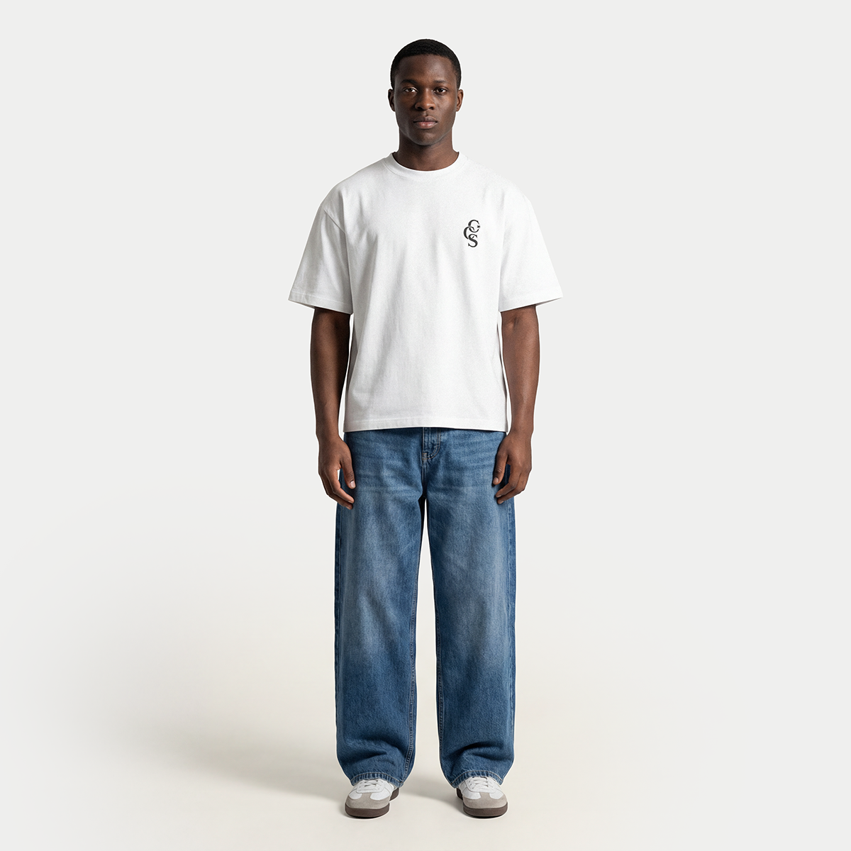 Full body model wearing white CCS t-shirt by Caracas Merch