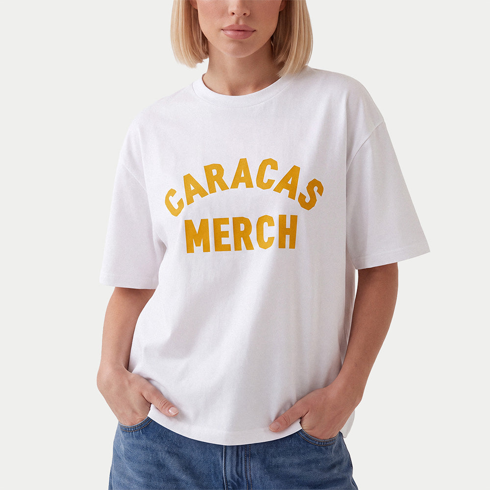Modelo con camiseta oversized blanca Caracas Merch con logo arqueado en naranja al frente