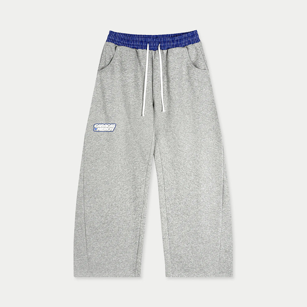 Front view of gray tracksuit sweatpants with blue waistband and Caracas Merch logo