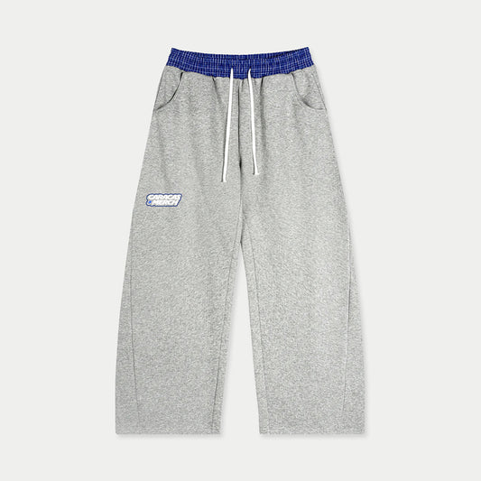 Front view of gray tracksuit sweatpants with blue waistband and Caracas Merch logo