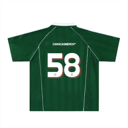 Green soccer-style jersey back view with “CARACASMERCH” text on upper back and large number 58 in white with red outline – Caracas Merch