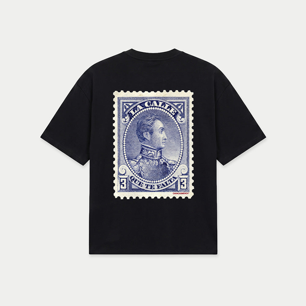 Black oversized t-shirt back view with large vintage blue postage stamp graphic featuring a classic portrait and “la calle que te falta” text – Caracas Merch