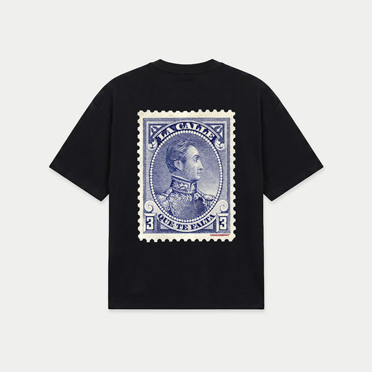 Black oversized t-shirt back view with large vintage blue postage stamp graphic featuring a classic portrait and “la calle que te falta” text – Caracas Merch