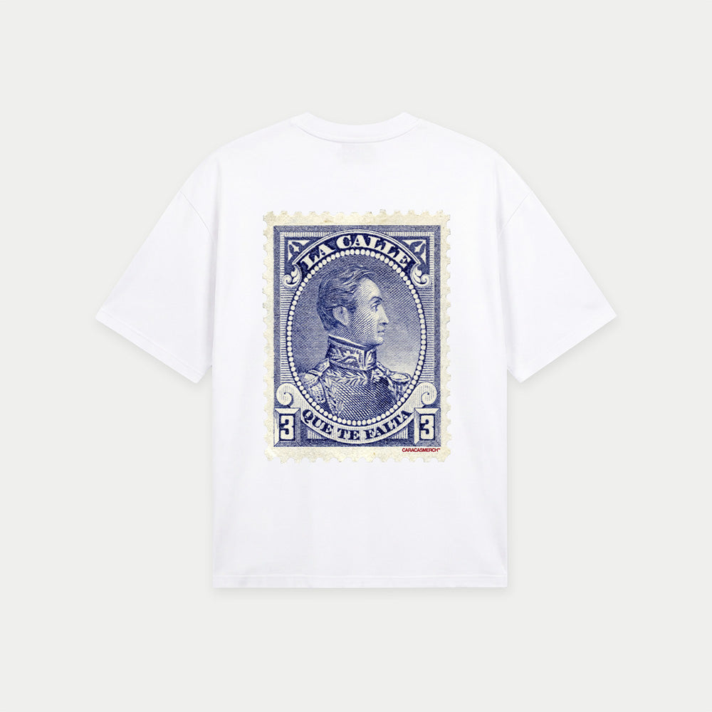 White oversized t-shirt back view with large vintage blue postage stamp graphic featuring a classic portrait and “la calle que te falta” text – Caracas Merch