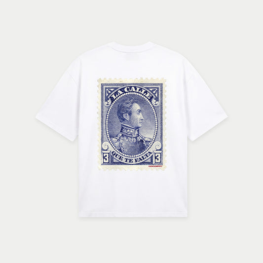 White oversized t-shirt back view with large vintage blue postage stamp graphic featuring a classic portrait and “la calle que te falta” text – Caracas Merch