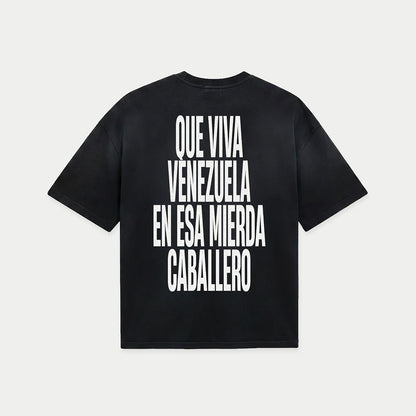 Black oversized t-shirt back view with bold black text graphic reading “Que viva Venezuela en esa mierda caballero” – Caracas Merch
