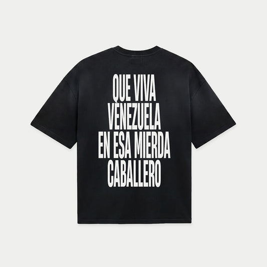Black oversized t-shirt back view with bold black text graphic reading “Que viva Venezuela en esa mierda caballero” – Caracas Merch
