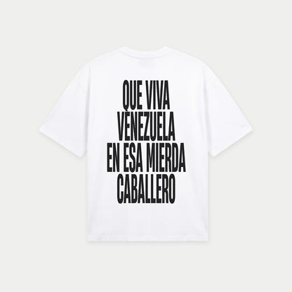 White oversized t-shirt back view with bold black text graphic reading “Que viva Venezuela en esa mierda caballero” – Caracas Merch