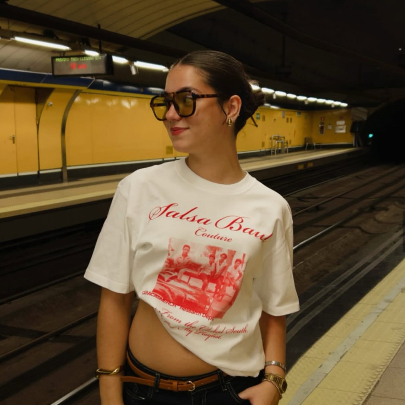 Model wearing white Salsa Baul Couture graphic t-shirt in a metro station in Europe