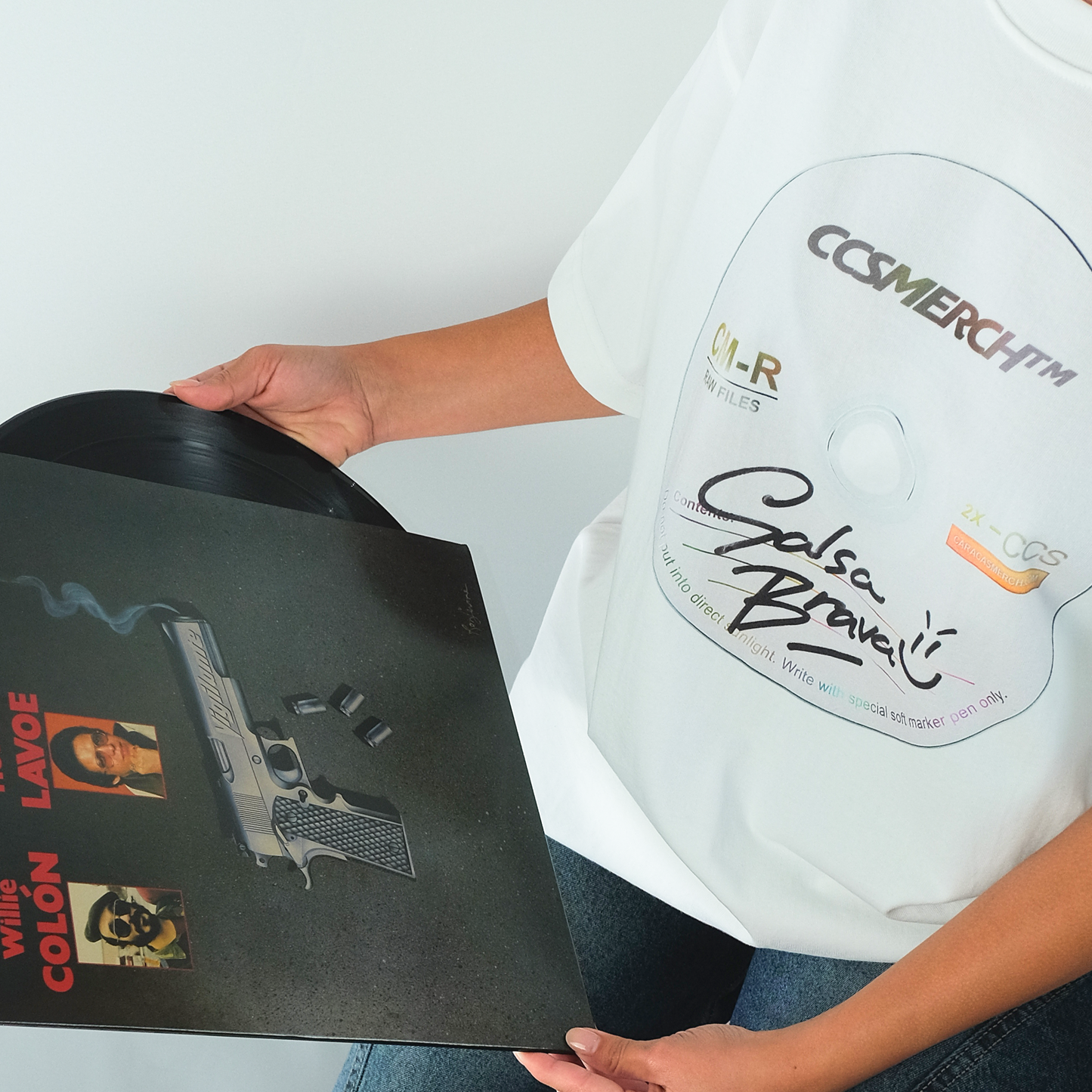 Model wearing Salsa Brava white graphic t-shirt holding vinyl record in editorial setting